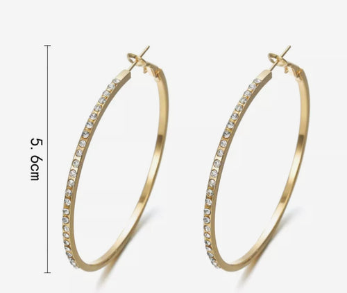 Gouden creolen met glinsterende steentjes en een elegante pouch als opbergzakje.