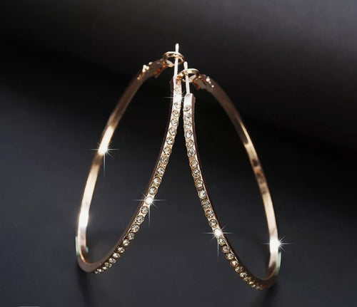 Gouden creolen met glinsterende steentjes en een elegante pouch als opbergzakje.